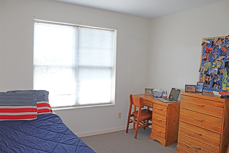 A bedroom inside of an apartment in 受托人的大厅. The room includes a bed, desk, and dresser.